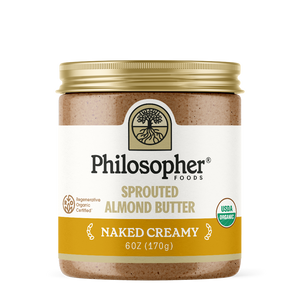 Image displays front of jar. Label displays image of tree with roots, "Philosopher Foods" in bold black text, "Sprouted Almond Butter" in gold, "Naked Creamy" in white, 6 ounce jar. Also shows label icons for USDA Certified organic and for Regenerative Organic Certified